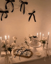 a table with a cake , candles , flowers , and bows on it .