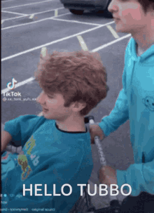 a boy in a wheelchair is being pushed by another boy in a blue shirt that says hello tubbo