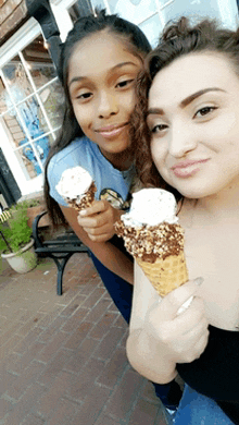 two girls holding ice cream cones in front of a store