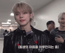 a young man wearing a black jacket with a red heart on the back