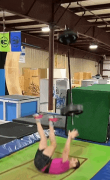 a woman is laying on her back on a trampoline in a gym