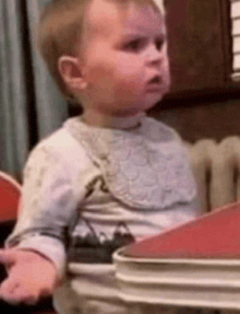 a baby wearing a bib is sitting in a high chair .