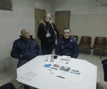 a man in a police uniform sits at a table with two other men