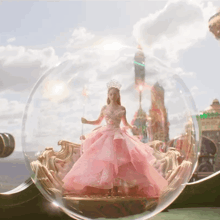 a doll in a pink dress and crown is in a glass ball
