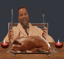 a man sitting at a table with a turkey and candles