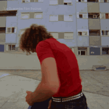 a man in a red shirt is standing in front of a building with la guarimba film festival written on it