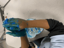 a child playing with blue slime on a table