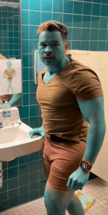 a man with blue paint on his face is standing in a bathroom