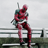 deadpool is sitting on a bench looking at his phone