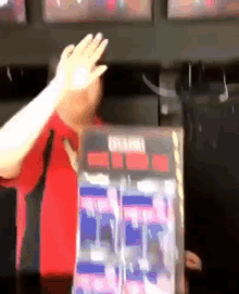 a man in a red shirt holds up his hand in front of a box that says ' coca cola '