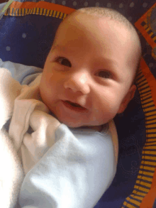 a baby is laying on a blue and orange blanket and smiling