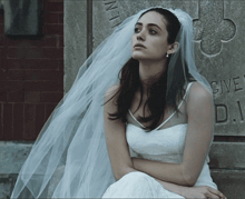 a woman in a wedding dress is sitting in front of a sign that says give d.i.