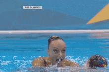 a woman in a colorful swimsuit is swimming in a pool with the nbc olympics logo on the bottom right