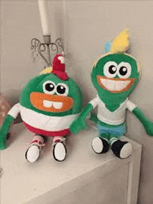 two stuffed animals are sitting on a white table holding hands .