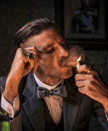 a man in a suit lighting a cigar with a lighter