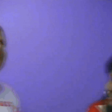 a close up of a woman 's face with a purple wall in the background