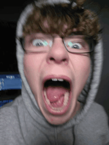 a man wearing glasses and a hoodie is making a funny face with his mouth open