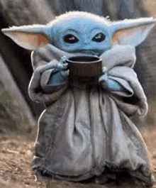 a baby yoda is holding a cup of coffee in his hand .