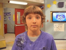 a young boy wearing a purple shirt is standing in front of a tv screen that says ' florida '