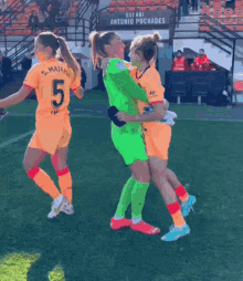 two female soccer players hugging each other on a field with a sign behind them that says " esta adi "