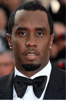 a close up of a man wearing a black suit and bow tie