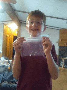 a young boy with glasses is holding a plastic bag in his hands