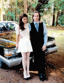 a man and a woman standing next to a car