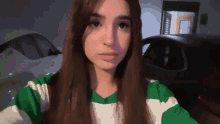 a girl in a green and white striped shirt looks at the camera