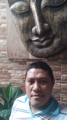 a man stands in front of a statue of a buddha 's face