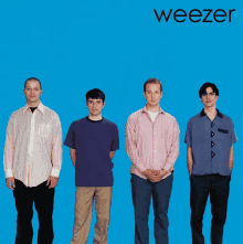 four men standing in front of a blue background with the word weezer