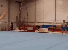 a man stands on a blue mat in a gym with a sign on the wall that says ' sydney '