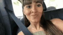 a woman is sitting in the back seat of a car making a funny face .