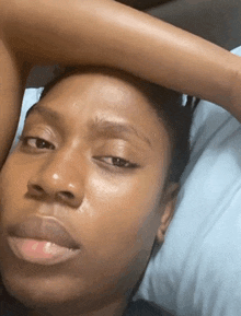 a close up of a woman laying on a bed with her hand on her head