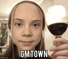 a woman holding a glass of wine with the words gmtown written on her face