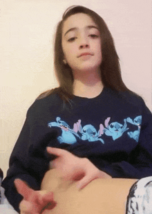 a girl wearing a blue sweatshirt with stitch on it is touching her belly