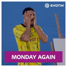 a man in a yellow evonik shirt covering his face