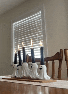 a row of ghost shaped candle holders with candles in them on a table