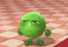 a green cartoon character is sitting on a checkered floor with a sad face .