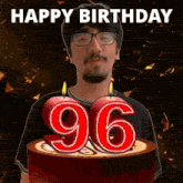a man with glasses stands in front of a cake with the number 96 on it