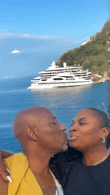 a man and woman are kissing in front of a large ship in the ocean