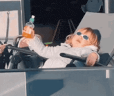 a little girl is sitting in a chair holding a bottle of water .