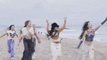 a group of women are dancing on a beach with one wearing a shirt that says ' a ' on it