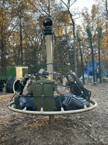 a group of people are sitting on a carousel in a park