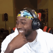 a man wearing headphones and a headband is smiling and laughing .