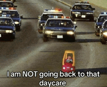 a child in a little tikes car is driving down a street with police cars