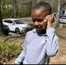 a young boy is talking on a cell phone in a park .