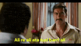a man with a mustache is talking to another man and the words ali re ali ata tuzt barri ali are on the screen