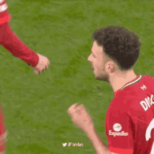 a soccer player is celebrating a goal with his fist in the air while another player looks on .