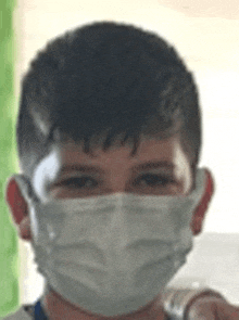 a young boy wearing a white face mask is smiling .