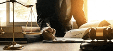 a man in a suit and tie is sitting at a desk writing on a piece of paper .